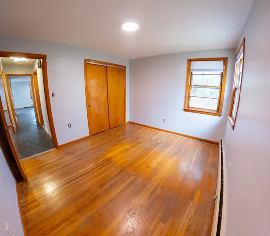 a view of an empty room with window and wooden floor