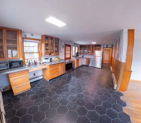 a kitchen with stainless steel appliances granite countertop a refrigerator a stove a sink and a dining table view