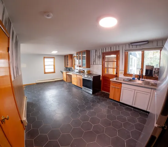 a large kitchen with granite countertop a stove a sink a window and dining table