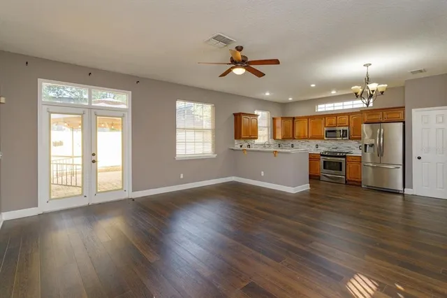 a view of an empty room with window and wooden floor