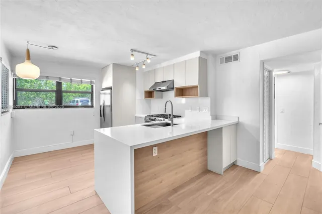 a kitchen with kitchen island a sink appliances and cabinets