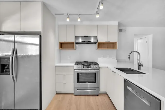 a kitchen with stainless steel appliances granite countertop a stove a refrigerator and a sink