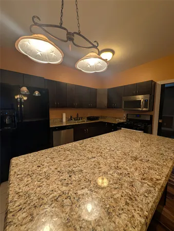 a kitchen with stainless steel appliances granite countertop a refrigerator and a stove top oven