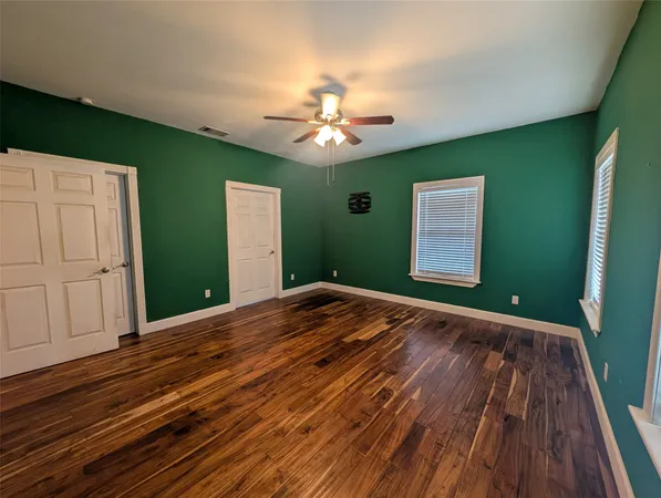 a view of a room with wooden floor and a ceiling fan