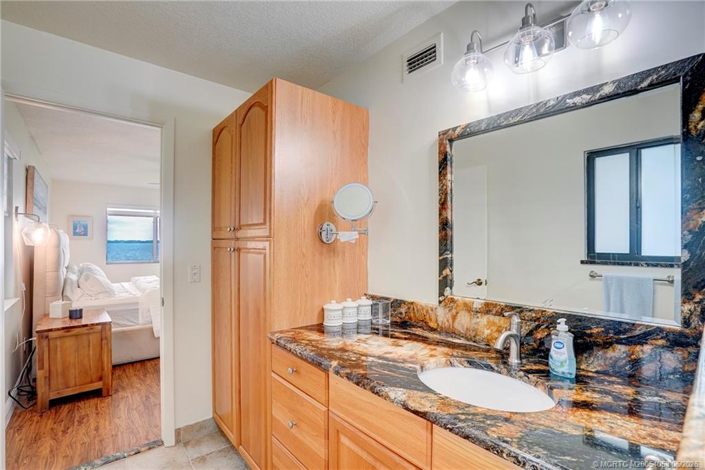 10 Northeast Plantation Road, Unit 101 Jensen Beach, FL 34957 - Photo 18 of 53 a bathroom with a granite countertop sink and a mirror