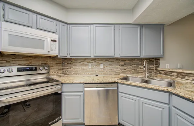 a kitchen with stainless steel appliances granite countertop a sink stove and cabinets