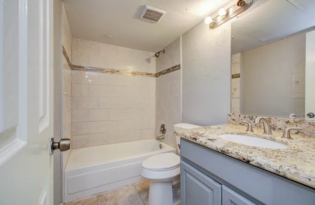 a bathroom with a granite countertop sink a toilet a mirror and shower