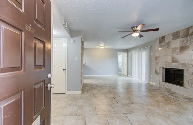 a view of a livingroom with a ceiling fan a fireplace and window