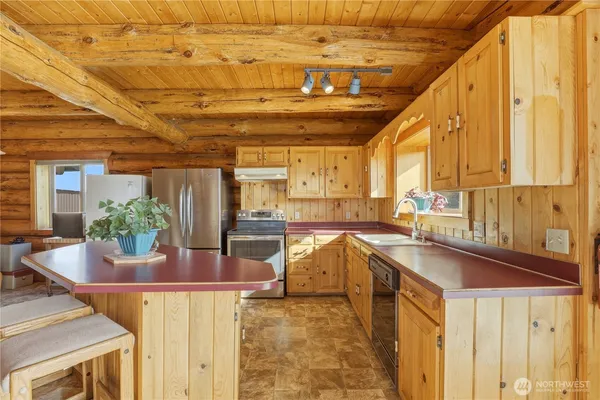 a room with stainless steel appliances kitchen island granite countertop furniture and a refrigerator