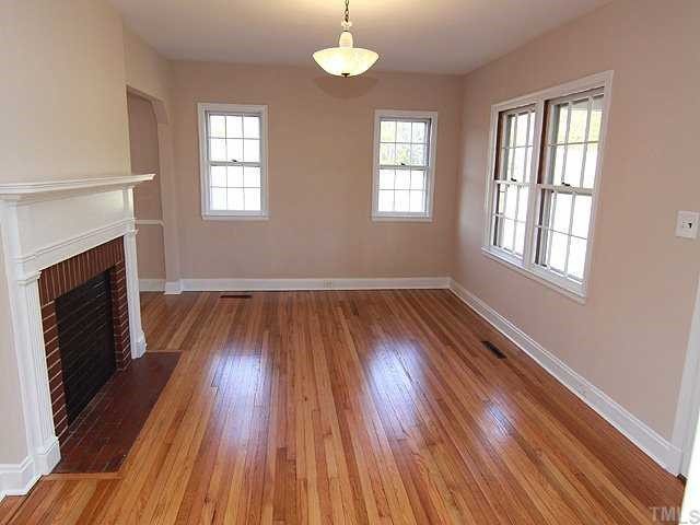 9923 North Roxboro Road Bahama, NC 27503 - Photo 4 of 12 an empty room with wooden floor fireplace and windows