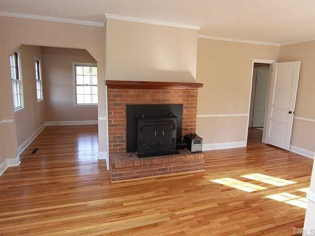 9923 North Roxboro Road Bahama, NC 27503 - Photo 7 of 12 a view of an empty room with wooden floor fireplace and a window