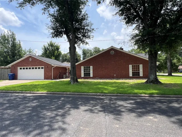 a view of a house with a yard and large tree