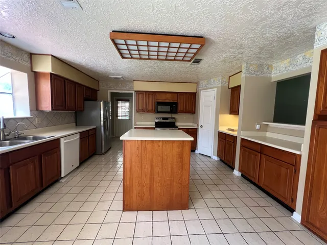 a large kitchen with stainless steel appliances granite countertop a stove a sink dishwasher and a refrigerator