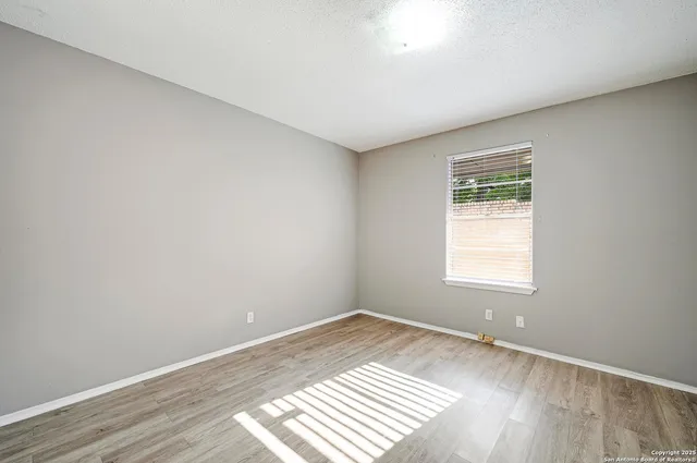 an empty room with wooden floor and a window