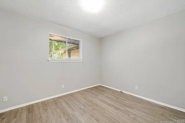an empty room with wooden floor and a window