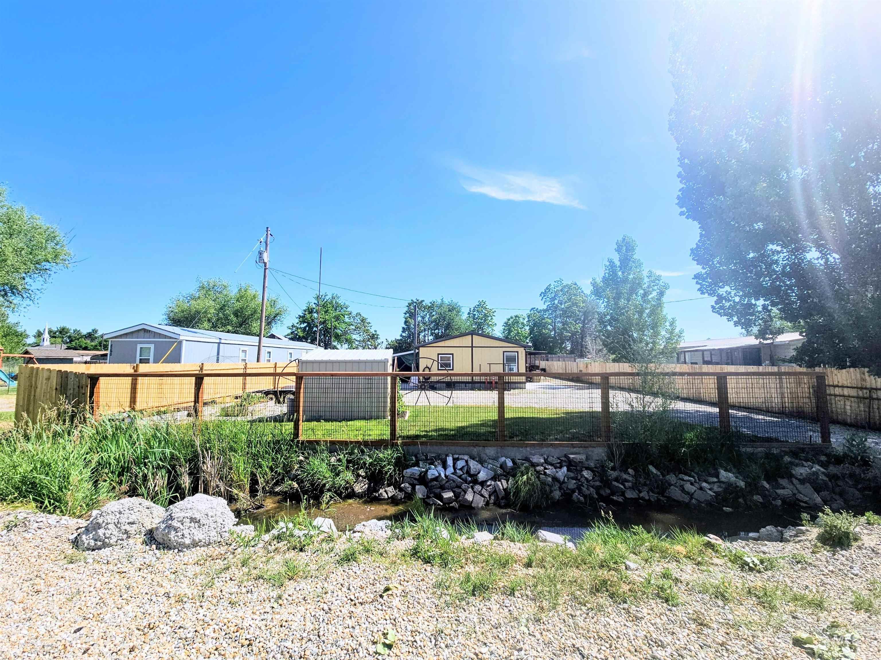8392 Main Street Letha, ID 83636 - Photo 31 of 31 Fenced property featuring a gravel driveway, a small water feature, and mature trees