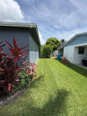 a backyard of a house with table and chairs plants and large tree
