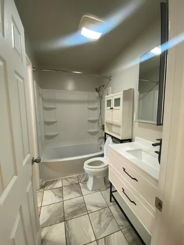 a bathroom with a granite countertop toilet a sink and a mirror