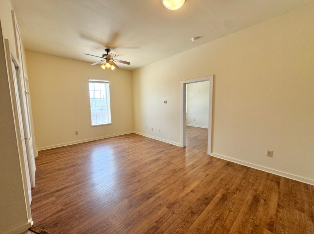 104 Depot Street, Unit B Elgin, TX 78621 - Photo 2 of 15 Spare room with ceiling fan, wood finished floors, and baseboards