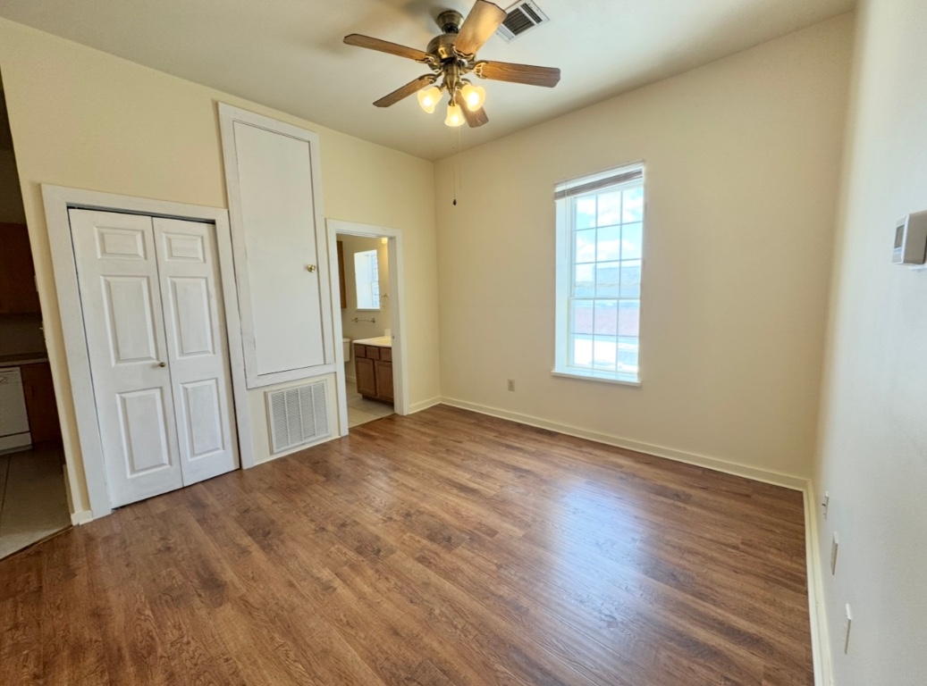 104 Depot Street, Unit B Elgin, TX 78621 - Photo 3 of 15 Unfurnished bedroom with wood finished floors, a closet, baseboards, ensuite bath, and ceiling fan