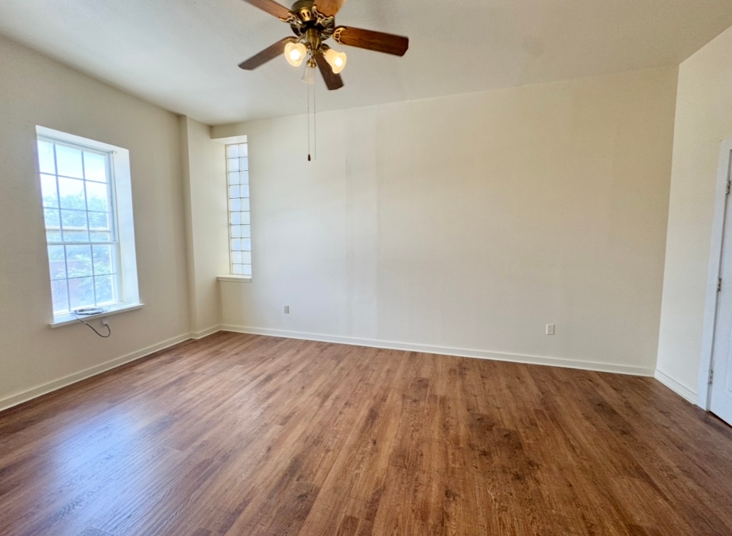 104 Depot Street, Unit B Elgin, TX 78621 - Photo 8 of 15 Empty room featuring wood finished floors, ceiling fan, and baseboards
