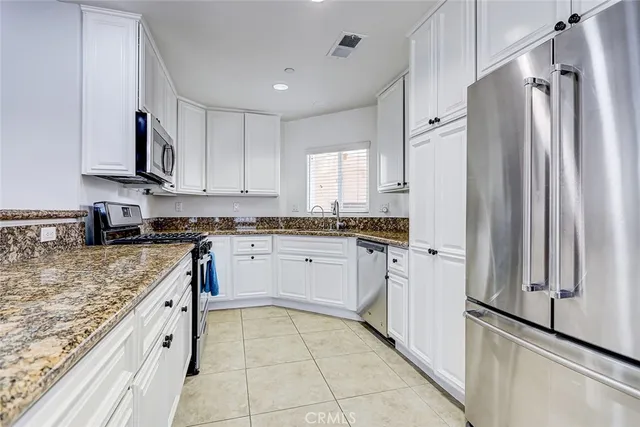 a kitchen with stainless steel appliances granite countertop a refrigerator and a stove top oven