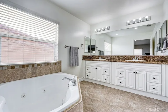 a bathroom with a granite countertop tub sink and mirror