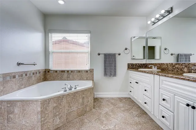 a bathroom with a granite countertop tub sink and mirror