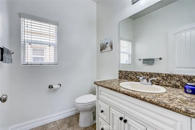a bathroom with a granite countertop sink a mirror and a toilet