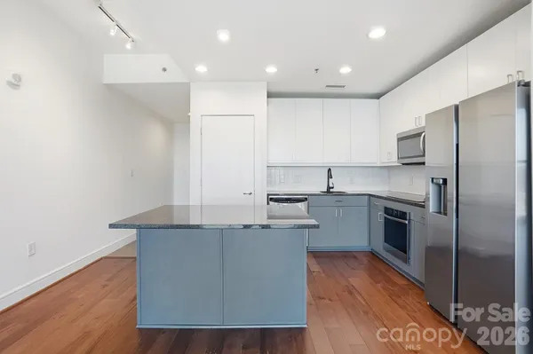 a utility room with stainless steel appliances white cabinets and a stove top oven