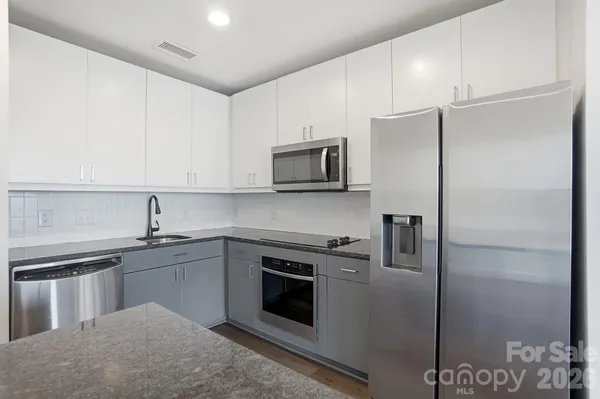 a kitchen with stainless steel appliances granite countertop a refrigerator stove and sink