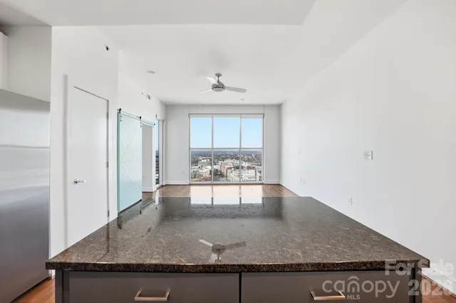 a kitchen with stainless steel appliances granite countertop a stove top oven a refrigerator a sink and chairs