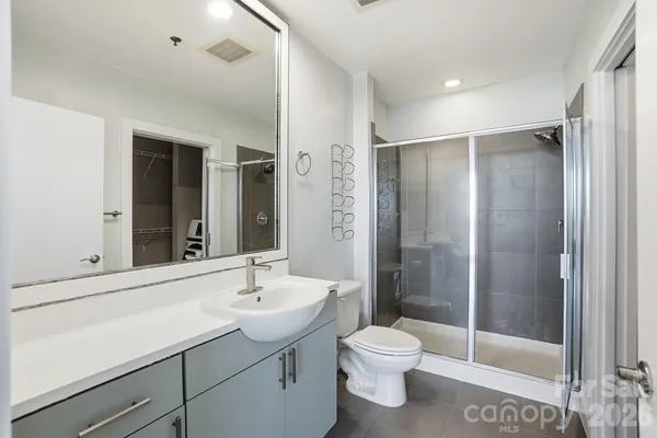 a bathroom with a shower sink vanity mirror and toilet