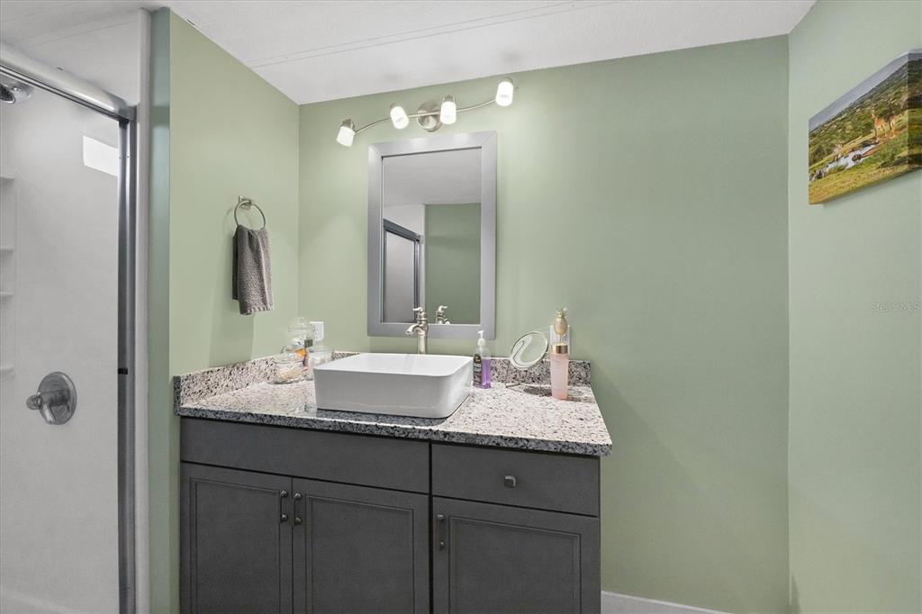 1891 Englewood Road, Unit 1 Englewood, FL 34223 - Photo 24 of 46 a bathroom with a granite countertop sink and a mirror