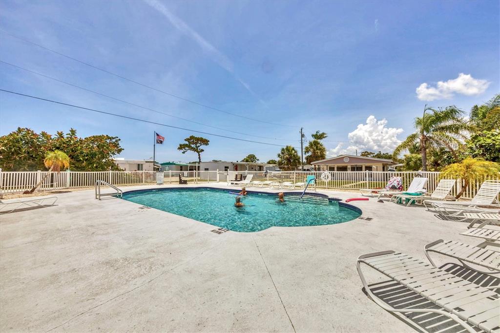 1891 Englewood Road, Unit 1 Englewood, FL 34223 - Photo 37 of 46 a view of a swimming pool with a lawn chairs and potted plants