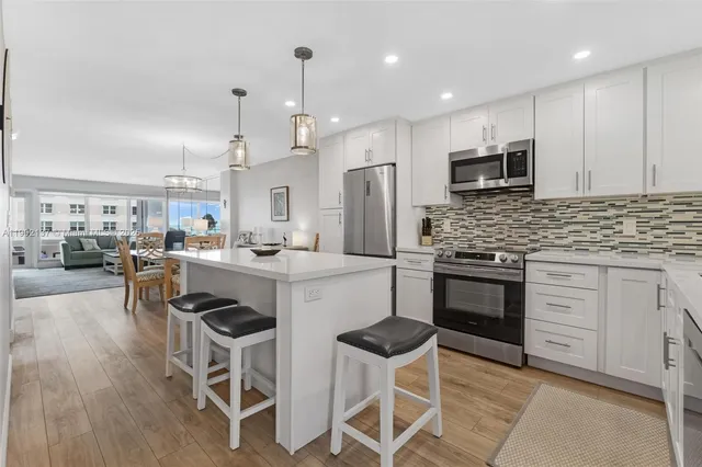 a kitchen with stainless steel appliances kitchen island granite countertop a stove top oven a sink a dining table and chairs