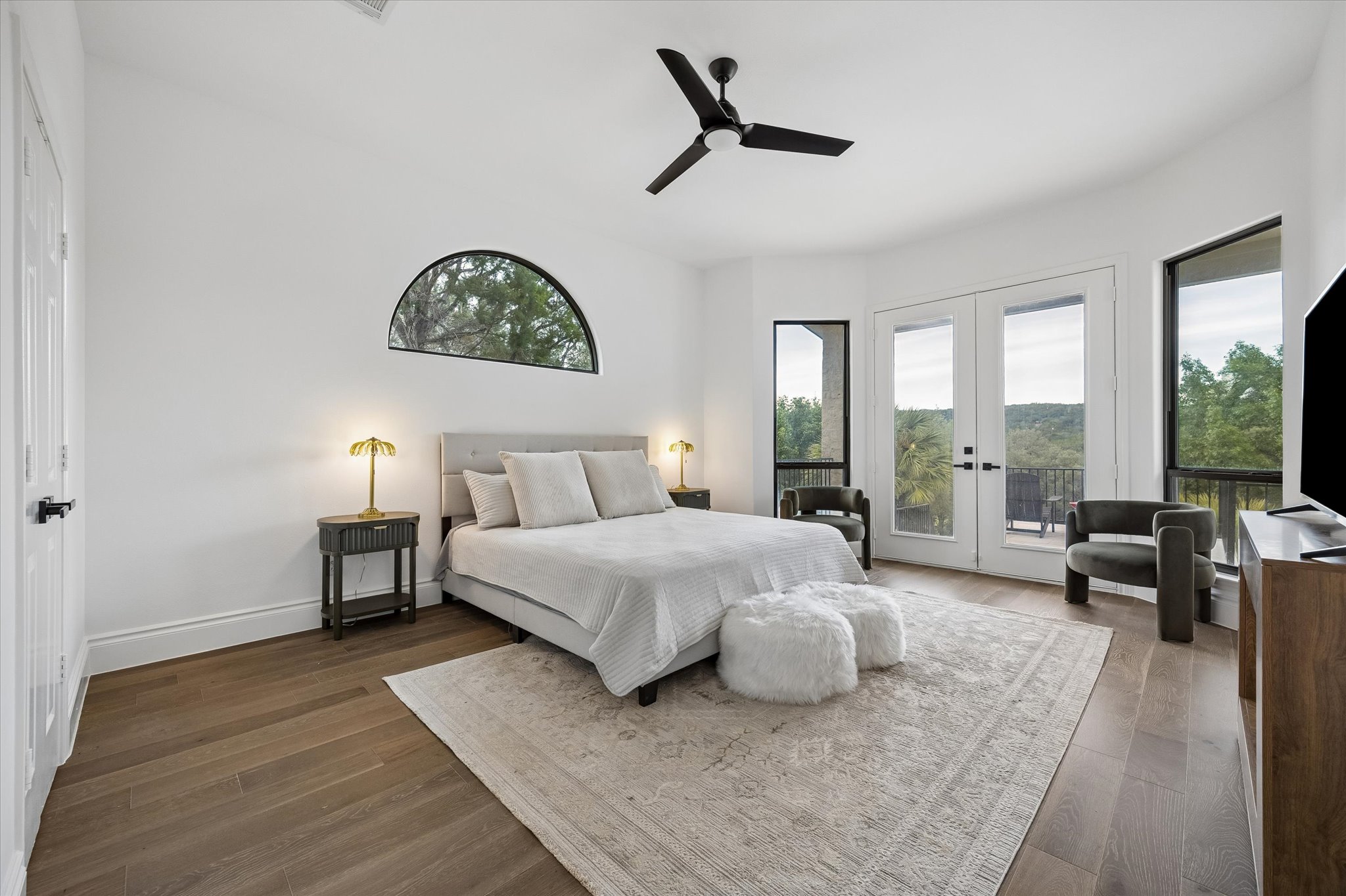 3719 Bee Creek Road Spicewood, TX 78669 - Photo 14 of 40 A well-lit bedroom features hardwood floors and a private balcony overlooking verdant landscapes.