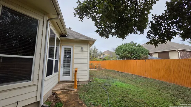 a backyard of a house with wooden fence and large trees