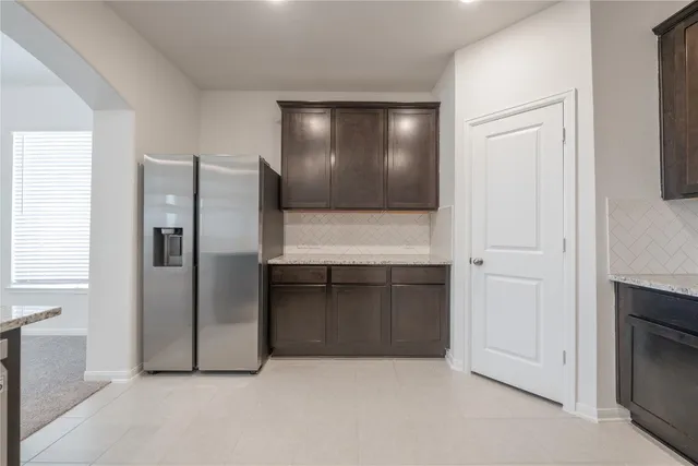 a view of a refrigerator in kitchen and an empty room