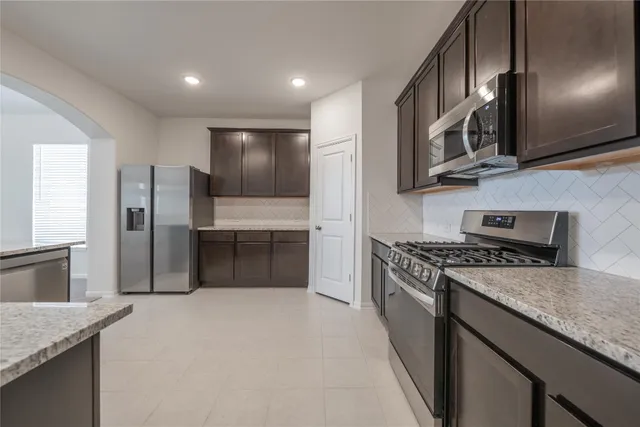 a kitchen with stainless steel appliances granite countertop a stove top oven a sink and a refrigerator