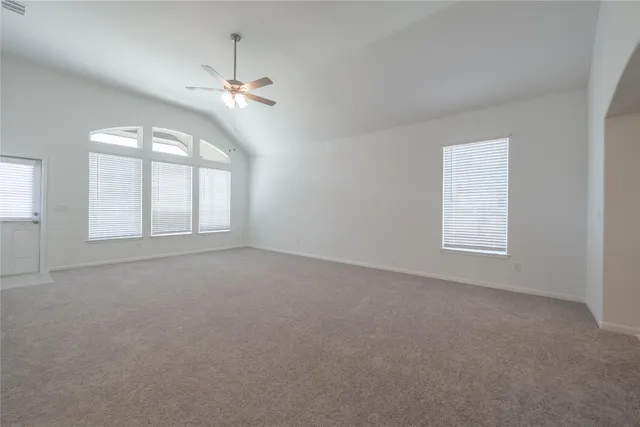 an empty room with windows and ceiling fan