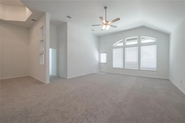 an empty room with windows and chandelier fan