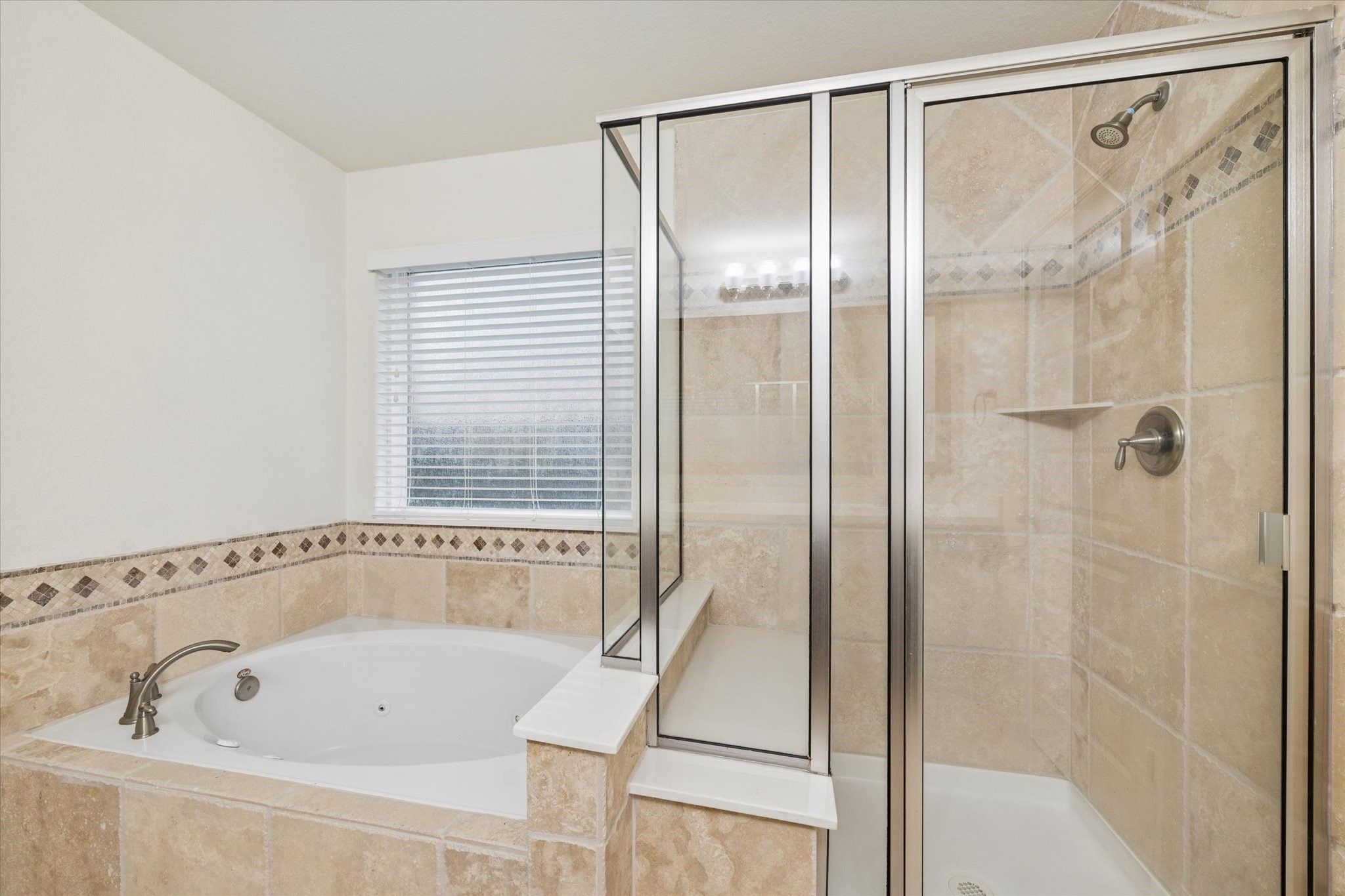 7015 Riata Hills Lane Spring, TX 77379 - Photo 17 of 33 The primary bath features a separate shower and soaking tub for a spa-like experience. The generously sized shower includes a built-in seating area, while the adjacent tub offers a relaxing retreat after a long day.