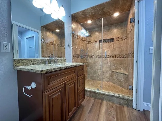 a bathroom with a granite countertop sink a toilet a mirror and shower