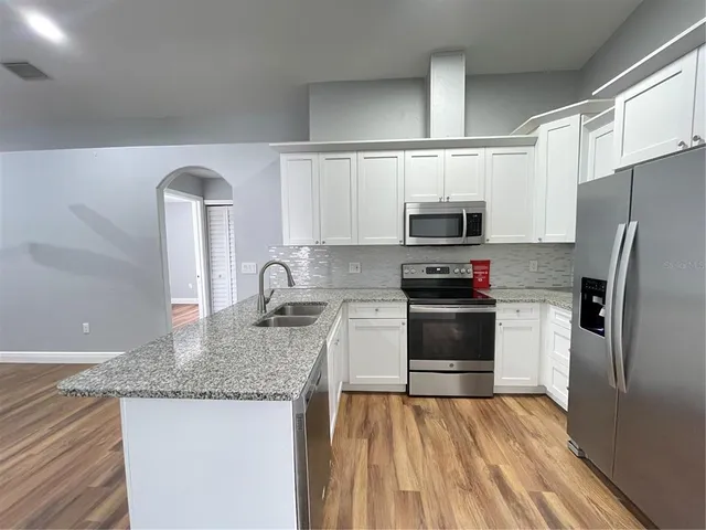 a kitchen with granite countertop a refrigerator stove and microwave