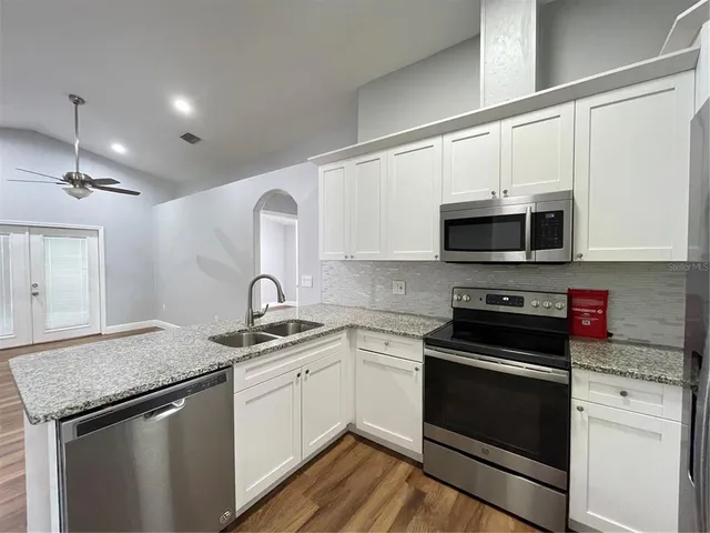 a kitchen with granite countertop white cabinets stainless steel appliances and a sink