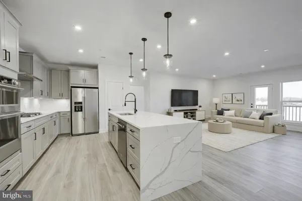 a large kitchen with stainless steel appliances lots of white cabinets and wooden floors