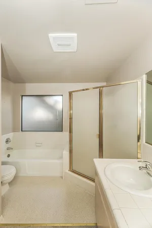 an empty room with chandelier fan and windows