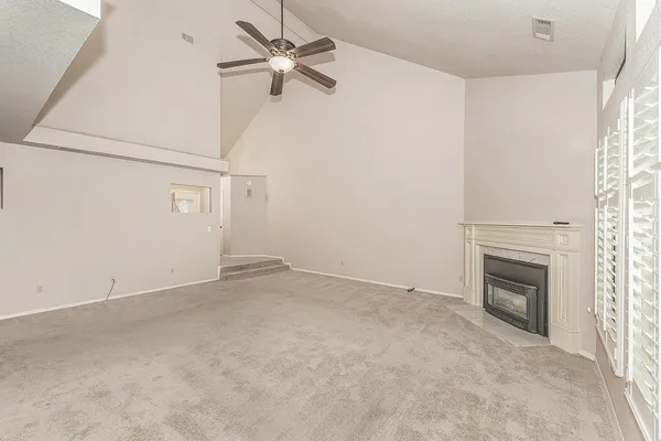 an empty room with a fireplace and a ceiling fan