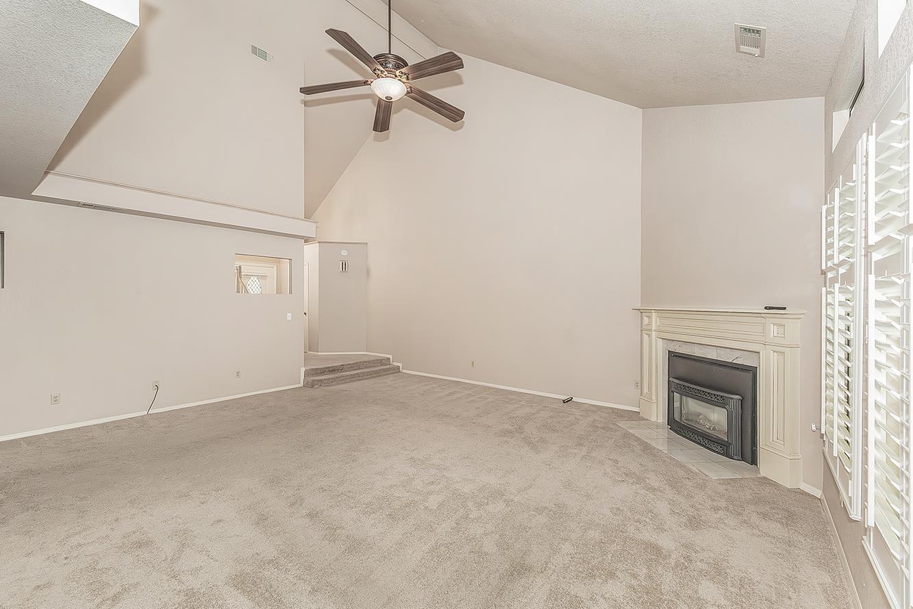 1282 West Flora Avenue Reedley, CA 93654 - Photo 8 of 49 an empty room with a fireplace and a ceiling fan